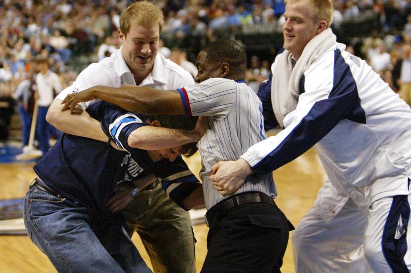 Mavericks owner Mark Cuban fights with the referee while Mavs' Evan Eschmeyer (right) moves...