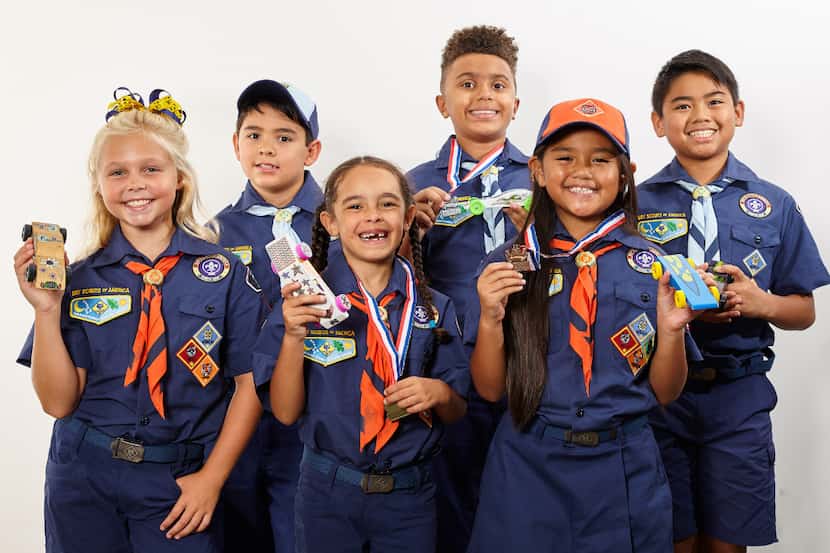 A group of scouts smiles for the camera while showing off their creatively decorated cars.