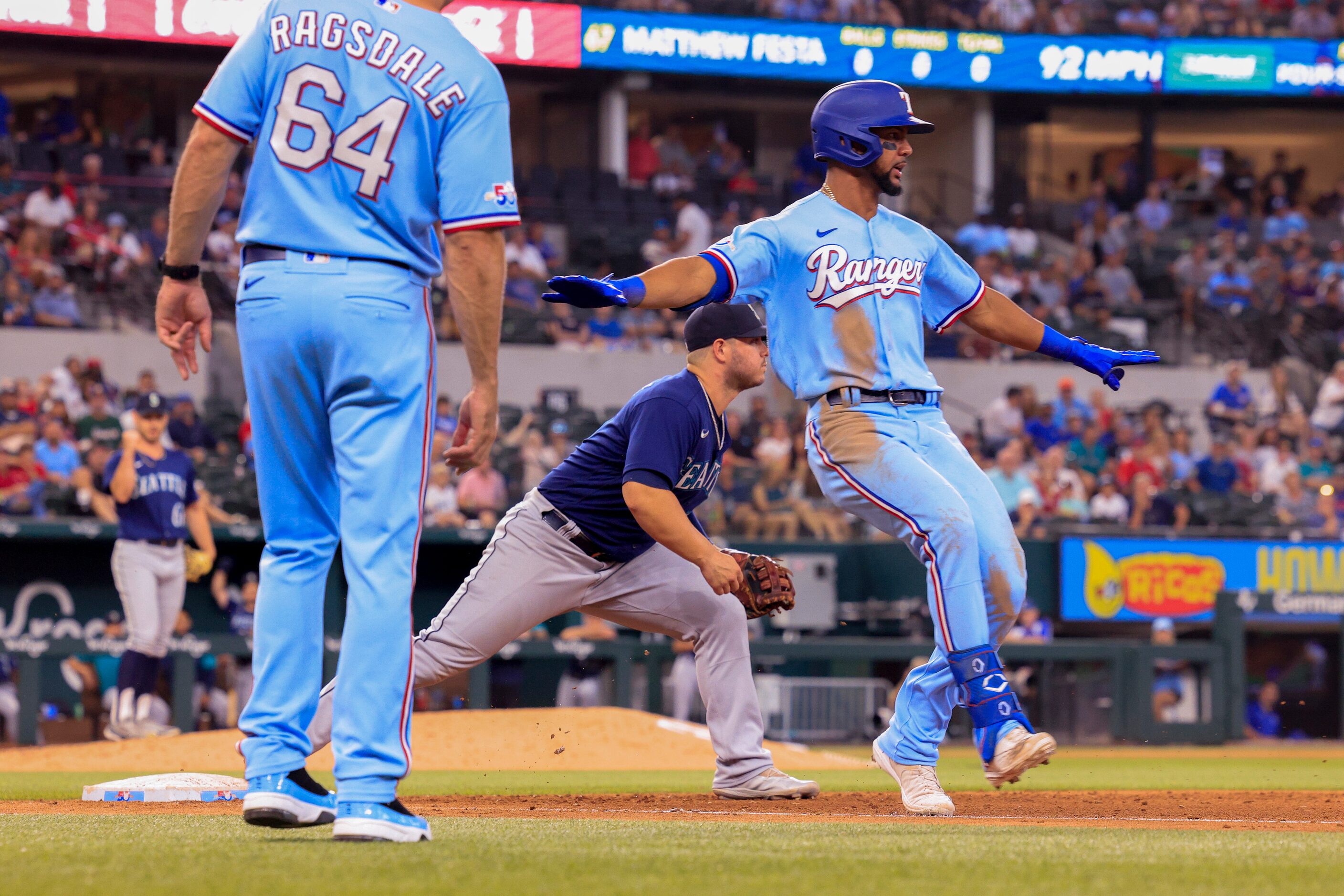 Texas Rangers center fielder Leody Taveras (3) signals safe after a close play at first base...