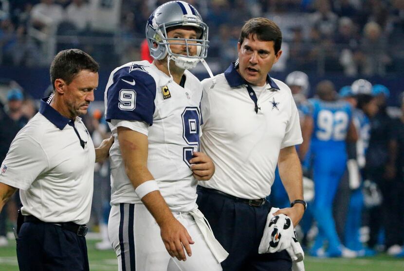 Dallas Cowboys quarterback Tony Romo (9) is helped off the field by trainers Britt Brown,...