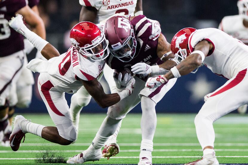 Texas A&M player is tackled by Arkansas Razorbacks defensive back Kevin Richardson II (30)...