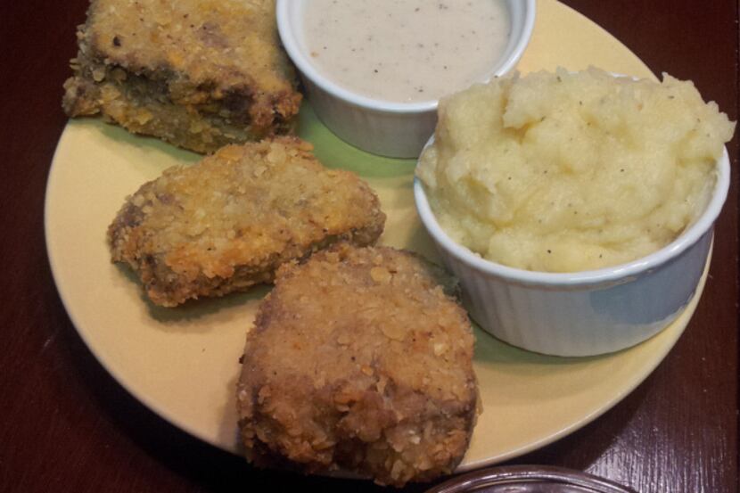 Southern Style Chicken-Fried Meatloaf is served with garlic mashed potatoes, cream gravy and...