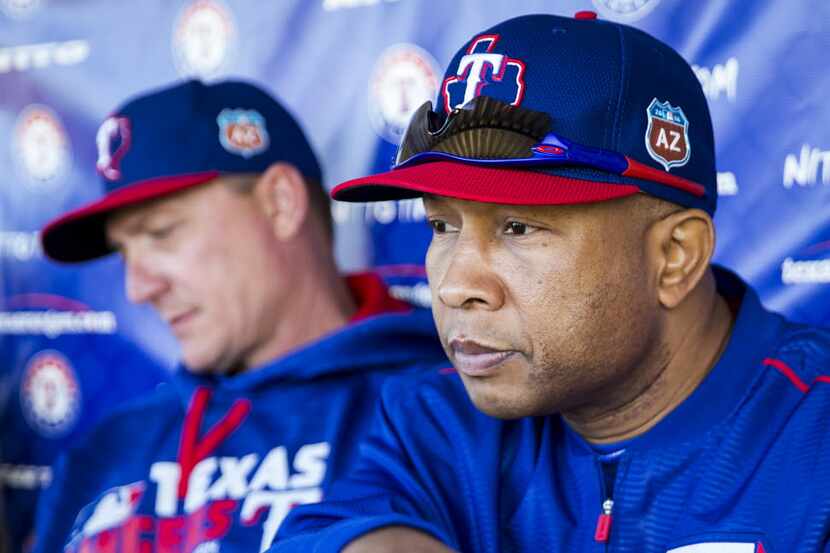Texas Rangers third base coach Tony Beasley sits in a dugout with manager Jeff Banister...