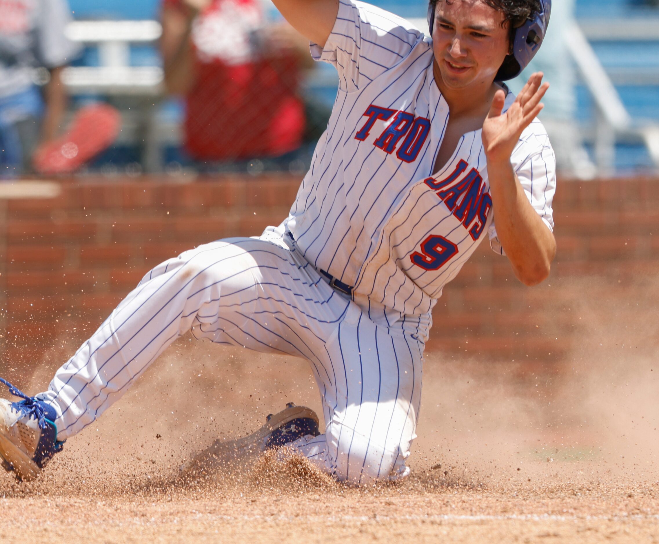 Trinity Christian players run to hug Joshua Liu (9) slides to home base for the game ending...