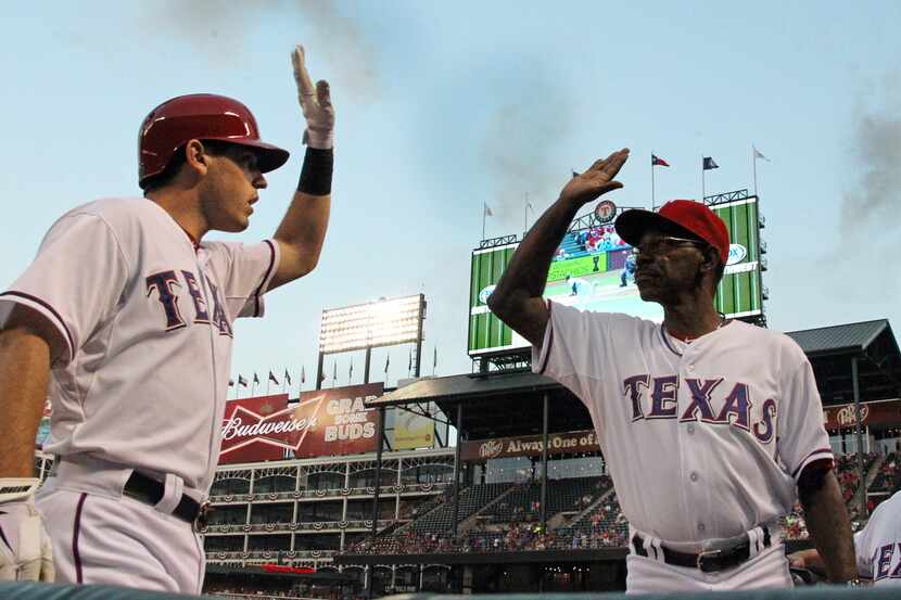 Texas' Ian Kinsler is greeted by manager Ron Washington at the dugout after hitting a solo...