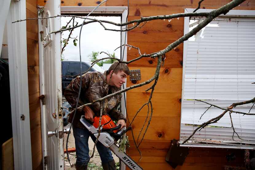 Brandon Sherwood prepares to cut down a tree that fell in the living room belonging to his...