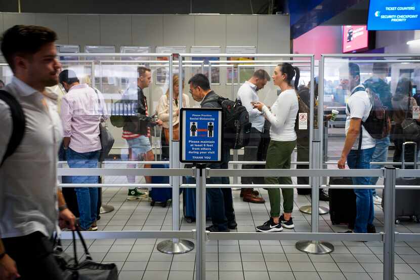 Departing passengers wait in line at a security checkpoint at Terminal C at DFW Airport on...