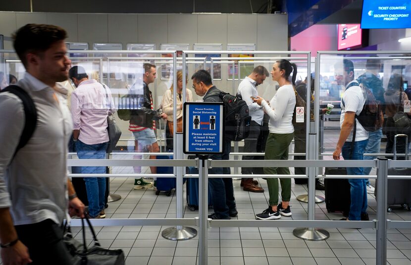 Departing passengers wait in line at a security checkpoint at Terminal C at DFW...