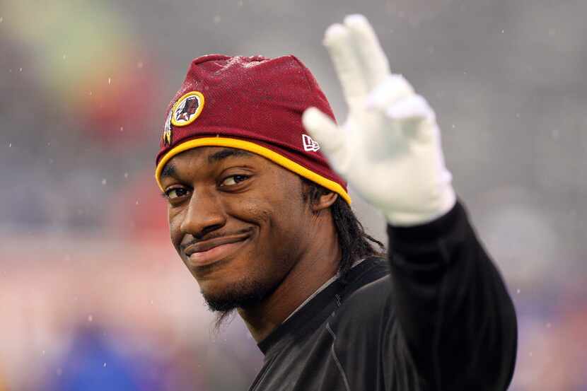 Washington Redskins quarterback Robert Griffin III (10) waves to fans before a game against...