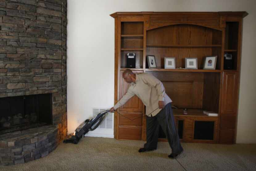 Kenneth Robinson vacuums the spacious living room of the Flower Mound home he's occupying in...