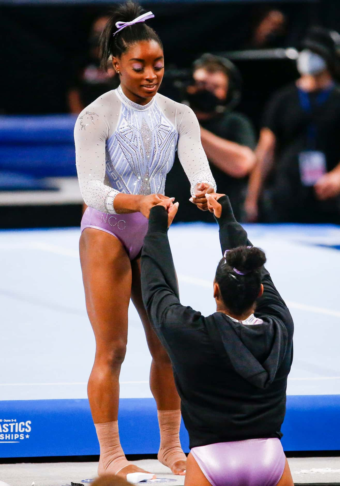 Simone Biles fist bumps a teammate before performing on the floor during day 1 of the senior...