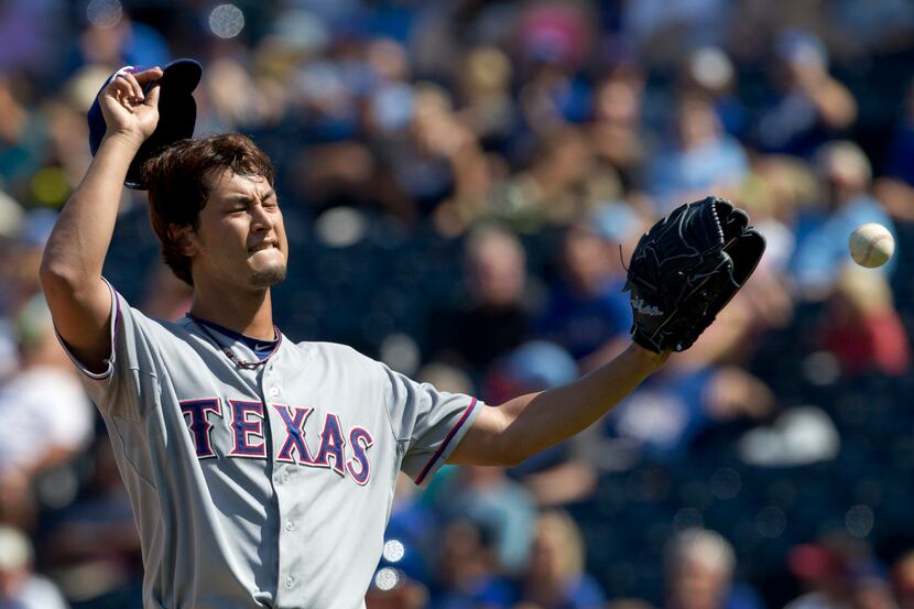 Texas Rangers starting pitcher Yu Darvish takes a new ball after giving up a walk in the...