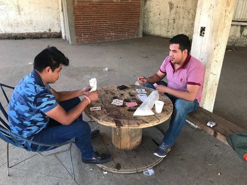 Gustavo Cortez plays cards with his cousin Cesar Cortez as they began their shift to help...
