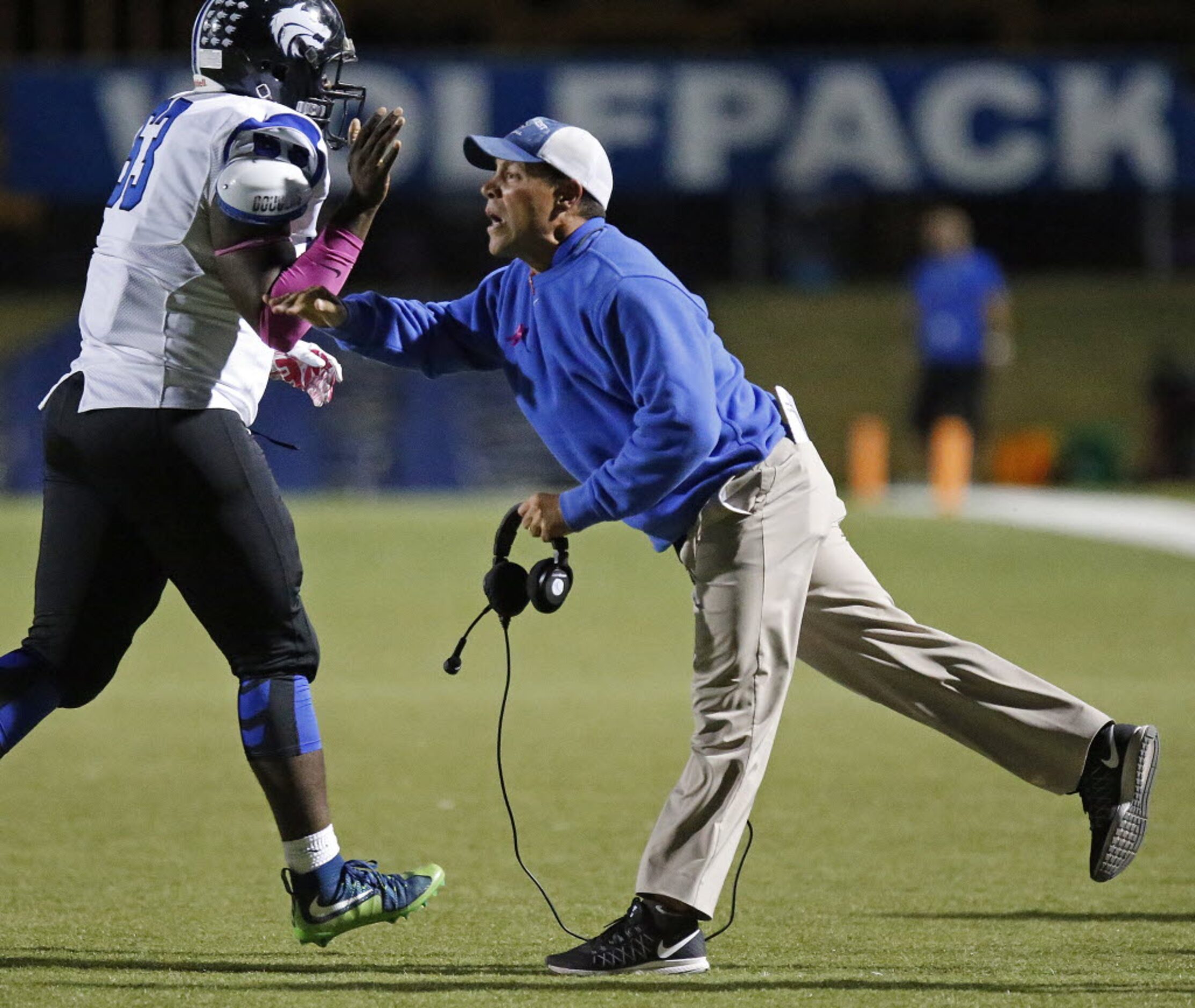 Plano West High School assistant coach David Hall (right) gives a high five to defensive...