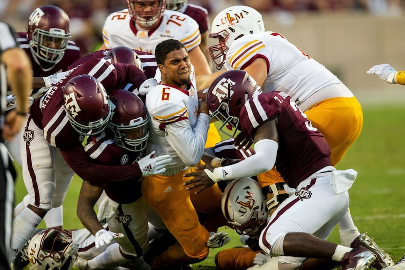 Louisiana Monroe quarterback Caleb Evans (6) is brought down by Texas A&M defenders after...