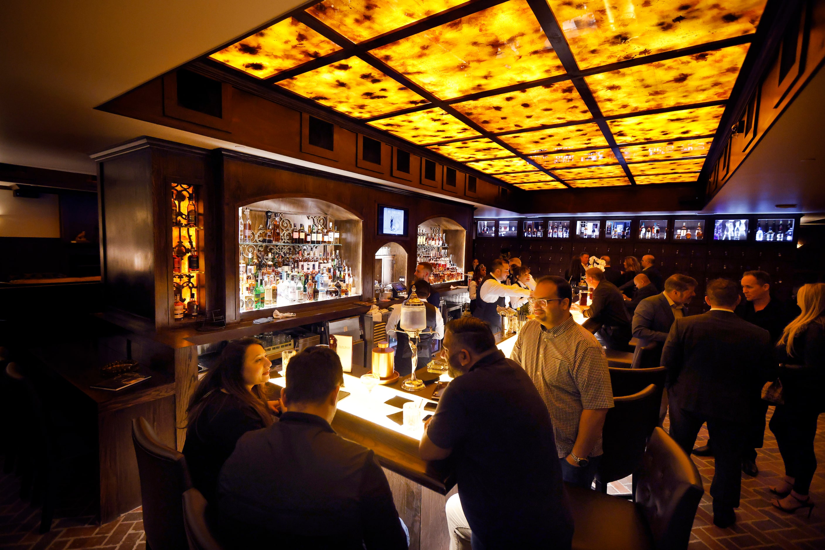 Guests attending a press event gathered around the main bar at Red Phone Booth, a speakeasy...