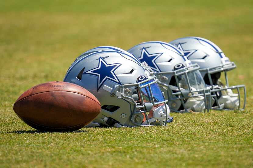 Dallas Cowboys helmets rest on the field during a training camp walk-through on Friday, Aug....