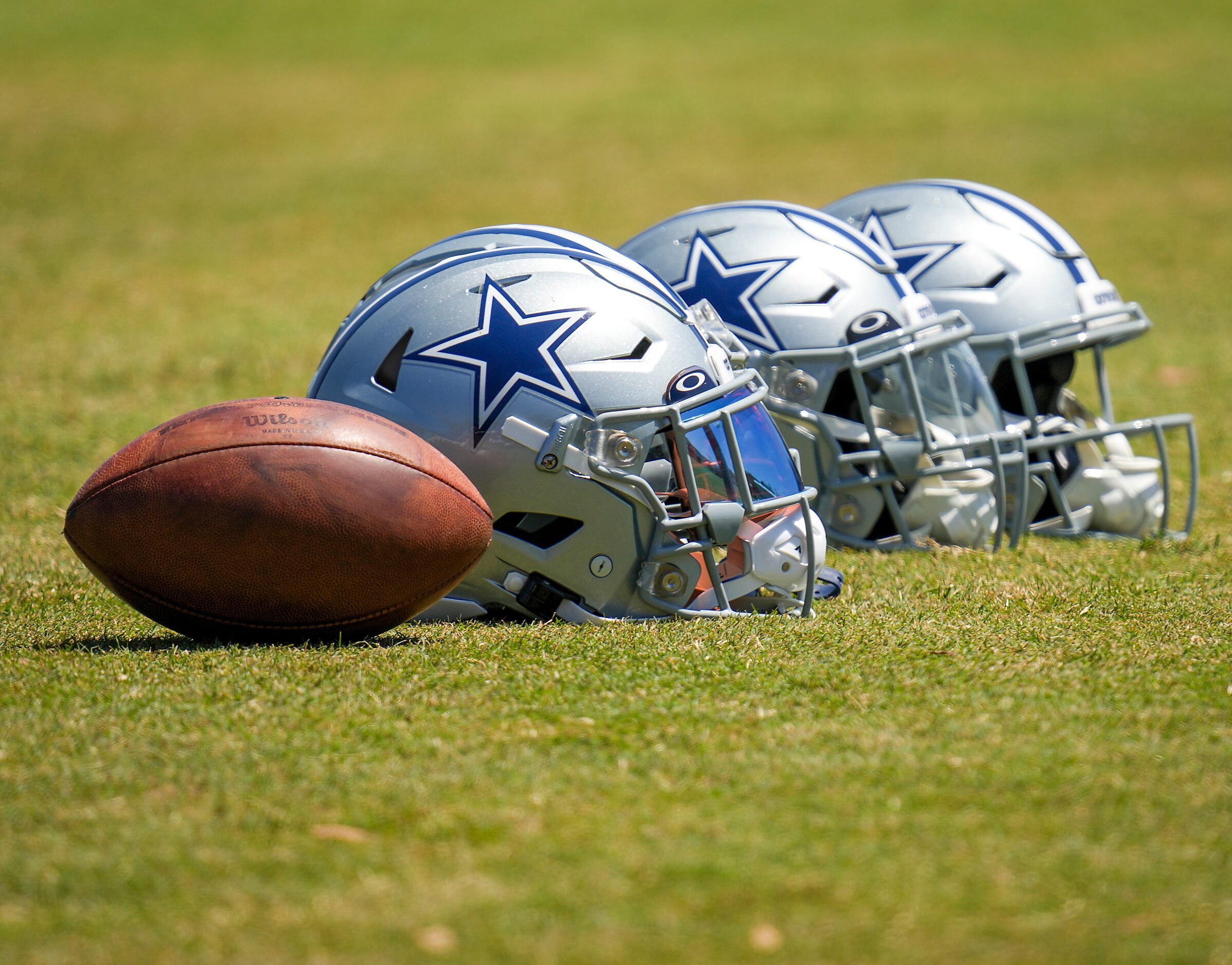 Dallas Cowboys helmets rest on the field during a training camp walk-through on Friday, Aug....