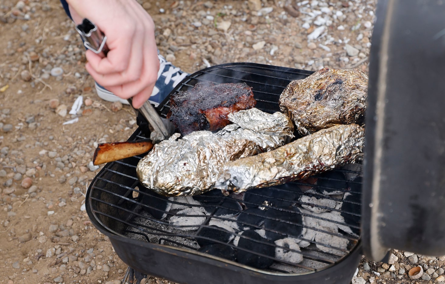 Dallas Cowboys fan Clay Mahone of Sherman, Texas, cooks meats before an NFL football game...