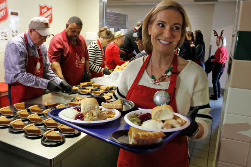 Volunteer Lisa Kerich carries a tray of food to waiting diners as the Salvation Army serves...