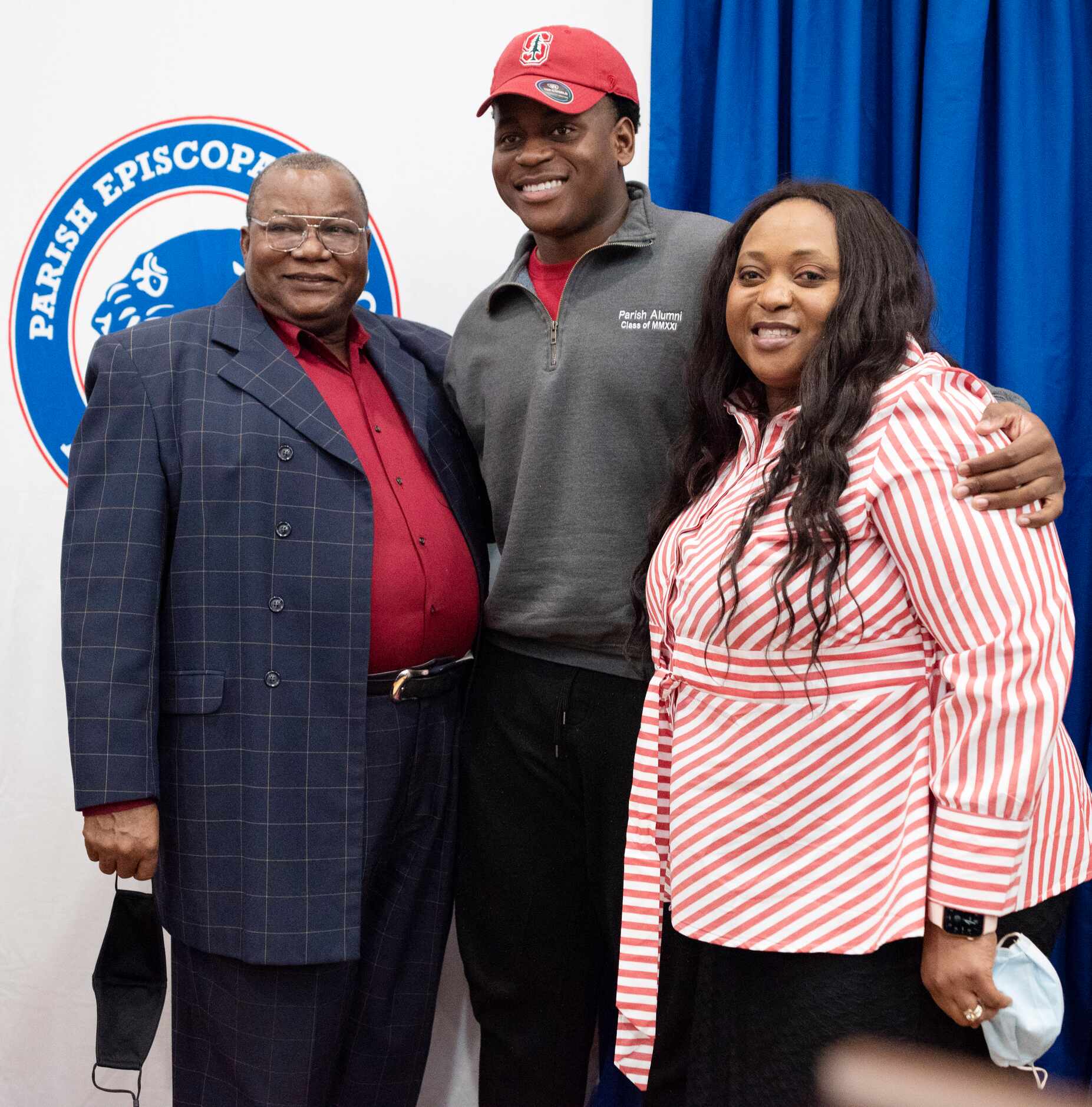 Senior Austin Uke poses for a photo with his parents Augustine Uke, left, and his mother...