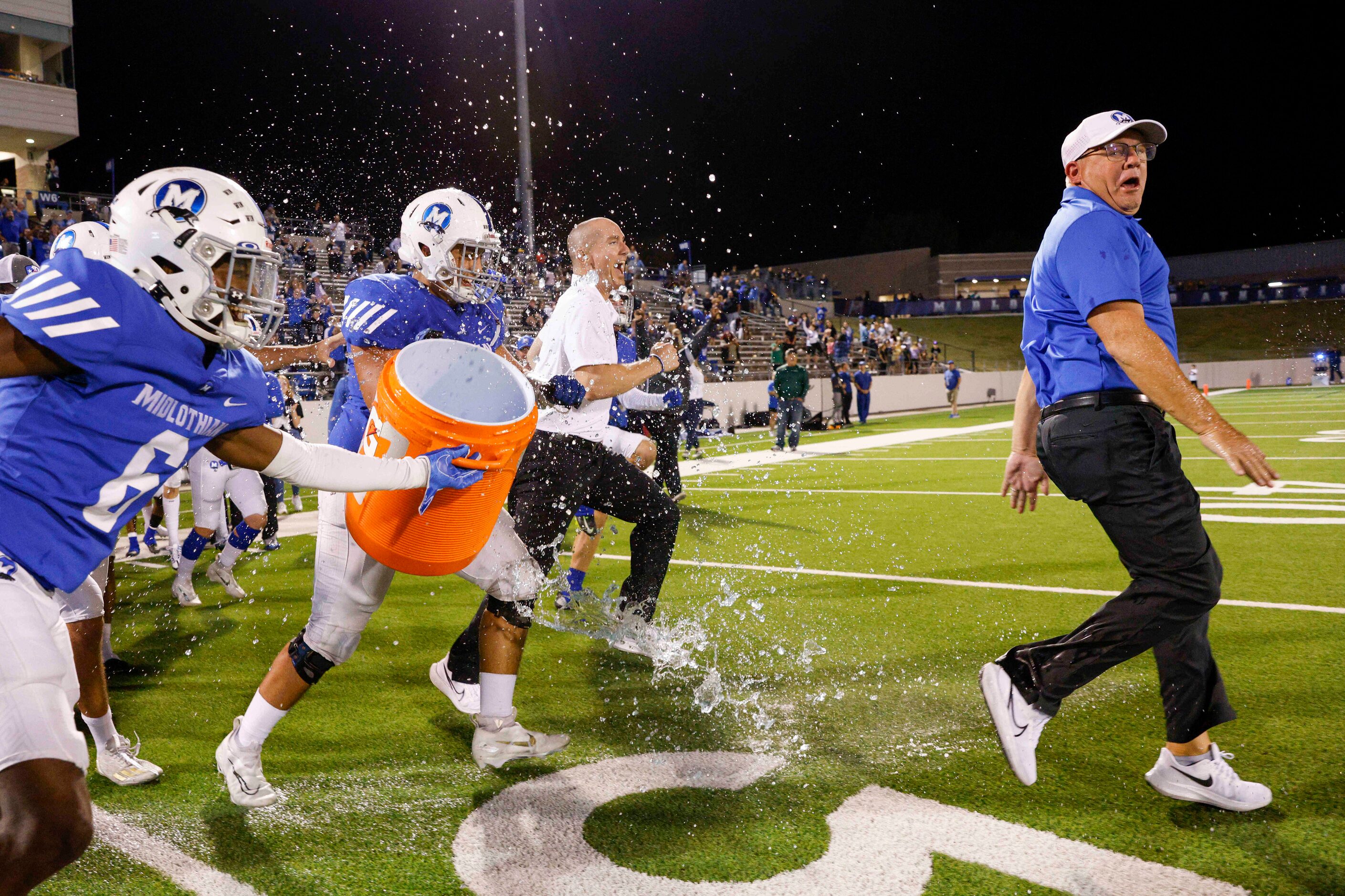 Midlothian head coach Doug Wendel tries to doge a Gatorade bath from defensive back Austin...