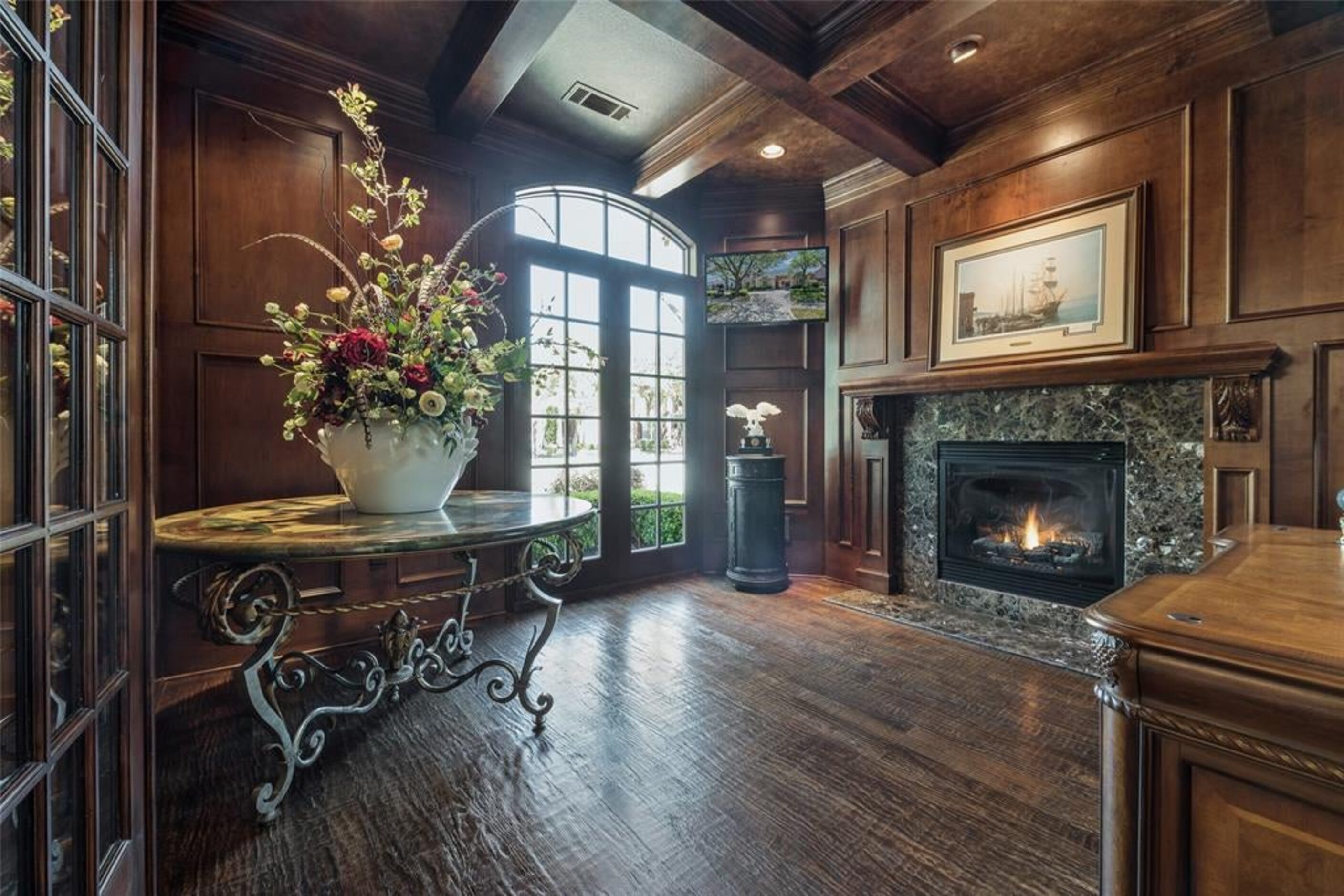 The library has dramatic tiered ceiling, fireplace and a wall of built-in shelving.