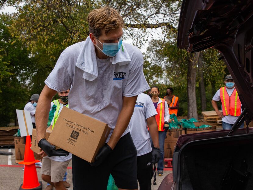 Former Dallas Mavericks player Dirk Nowitzki (left) loads a car during the Center Table Fall...