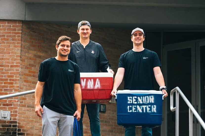 three young men with VNA coolers headed out to deliver Meals on Wheels