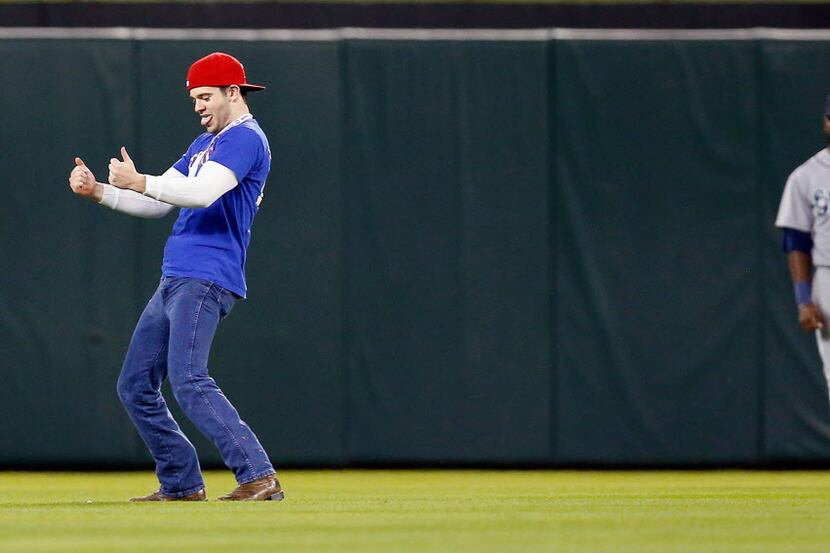 A fan runs on the field as the Seattle Mariners take on the Texas Rangers in the bottom of...