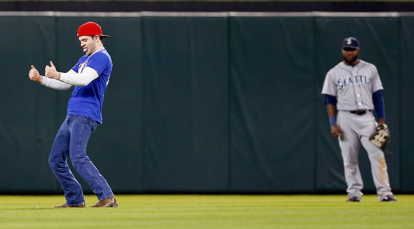 A fan runs on the field as the Seattle Mariners take on the Texas Rangers in the bottom of...