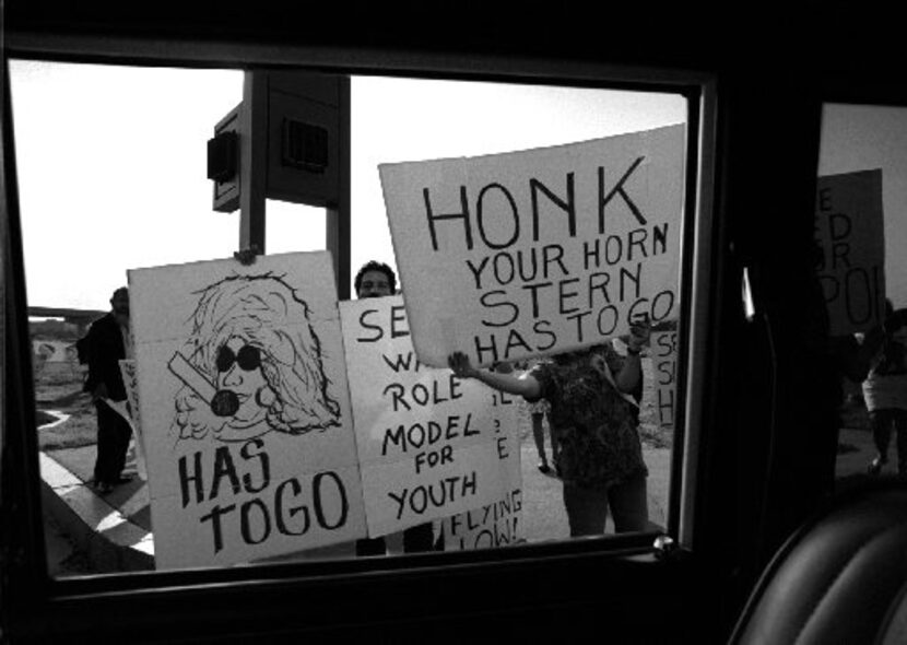 Protesters stand at the corner of O'Connor and Las Colinas boulevards near the offices of...