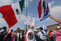 Una persona sostiene un cartel con la frase "Todos somos un mismo México" durante un mitin...