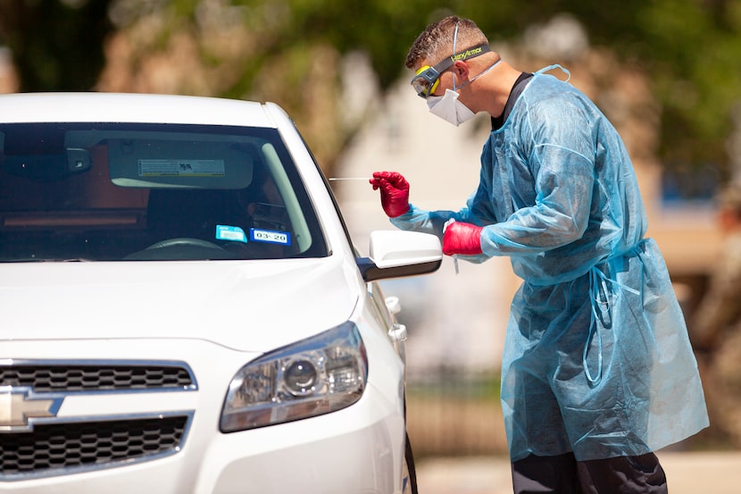 A medical worker conducts COVID-19 testing at the mobile drive-through site at Los Barrios...