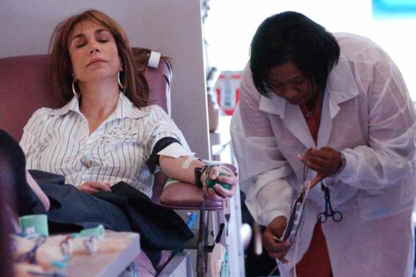 Carmen Eriksson (left) relaxes while giving blood as Carter BloodCare phlebotomist Jackie...