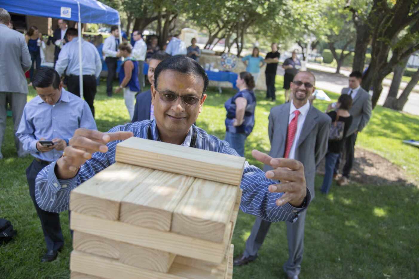Hemant Patel, a New York Life agent, carefully pulls a wood piece while he plays a life-size...