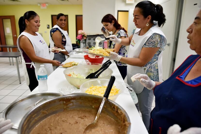 Anabel Vargas (left), waits for food orders of rolled tacos served by Brenda Ramirez (right)...