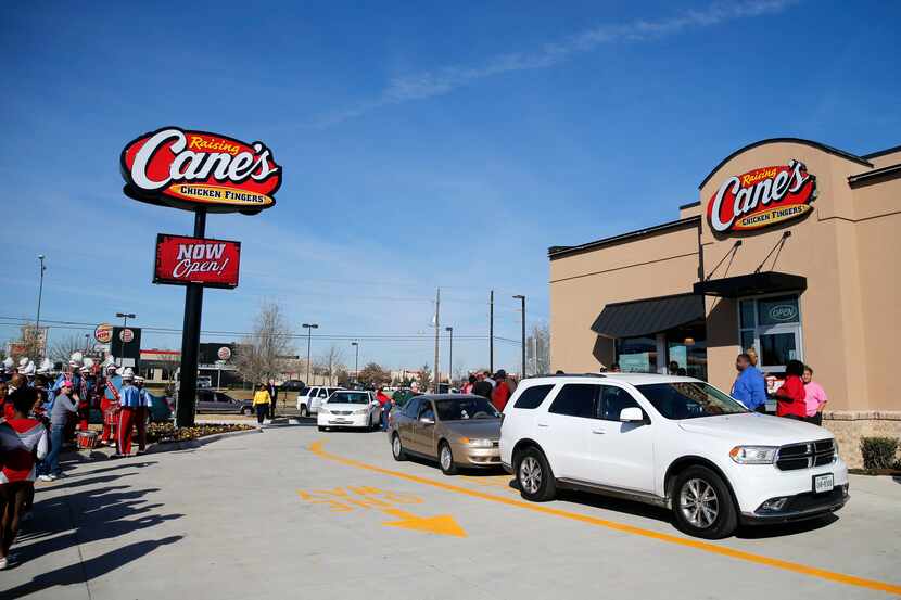 Cars line up at the grand opening of a Raising Cane's in Dallas in this file photo....