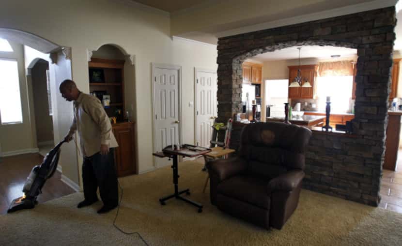 Kenneth Robinson vacuums the spacious living room of the Flower Mound home he's occupying.
