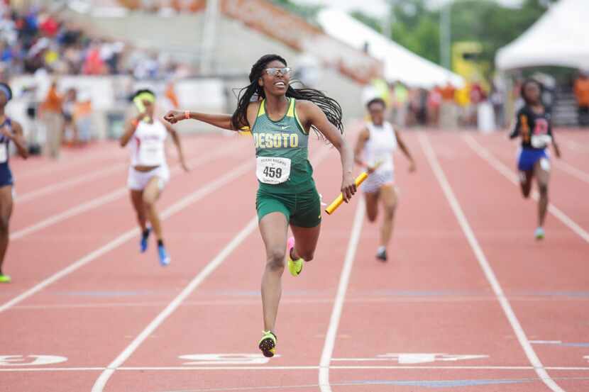 DeSoto's Rosaline Effiong (center) glances at the clock as she crosses the finish line...