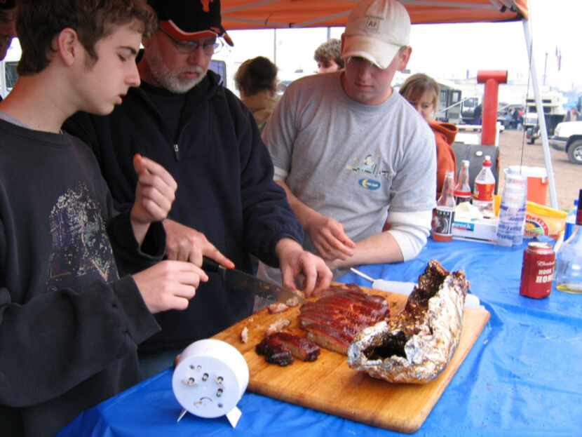 Kyle Mayberry (left) helps his father, Steve Mayberry, test some meat while family friend...