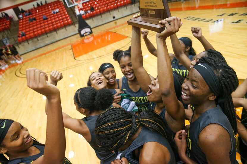 DeSoto guard Ash'a Thompson (25) hoists the trophy after defeating South Grand Prairie 51-34...
