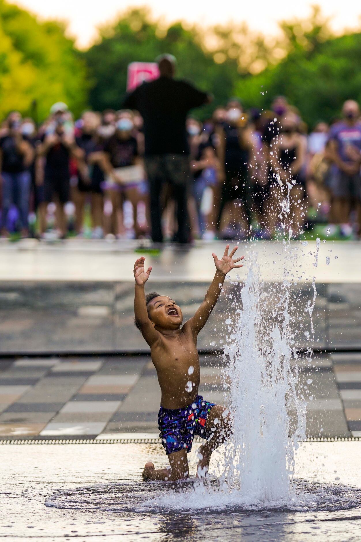 Massiah Webb, 4, plays in a fountain as DISD trustee Maxie Johnson addresses a rally for...