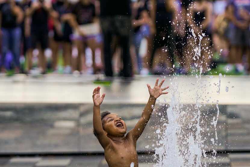Massiah Webb, 4, plays in a fountain as Dallas ISD trustee Maxie Johnson addresses a rally...