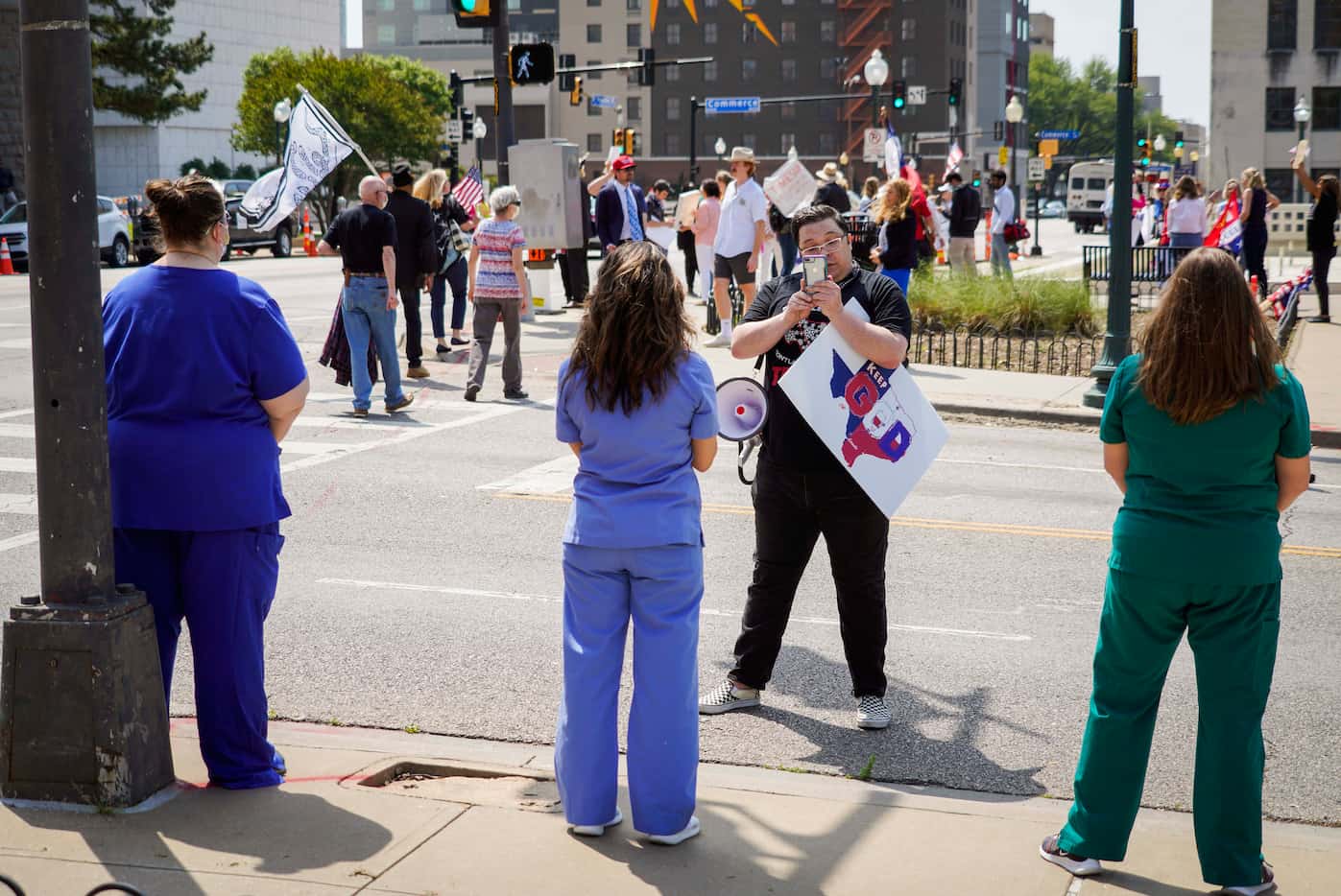 Three medical workers stand in silent counterprotest to a demonstration calling for the end...