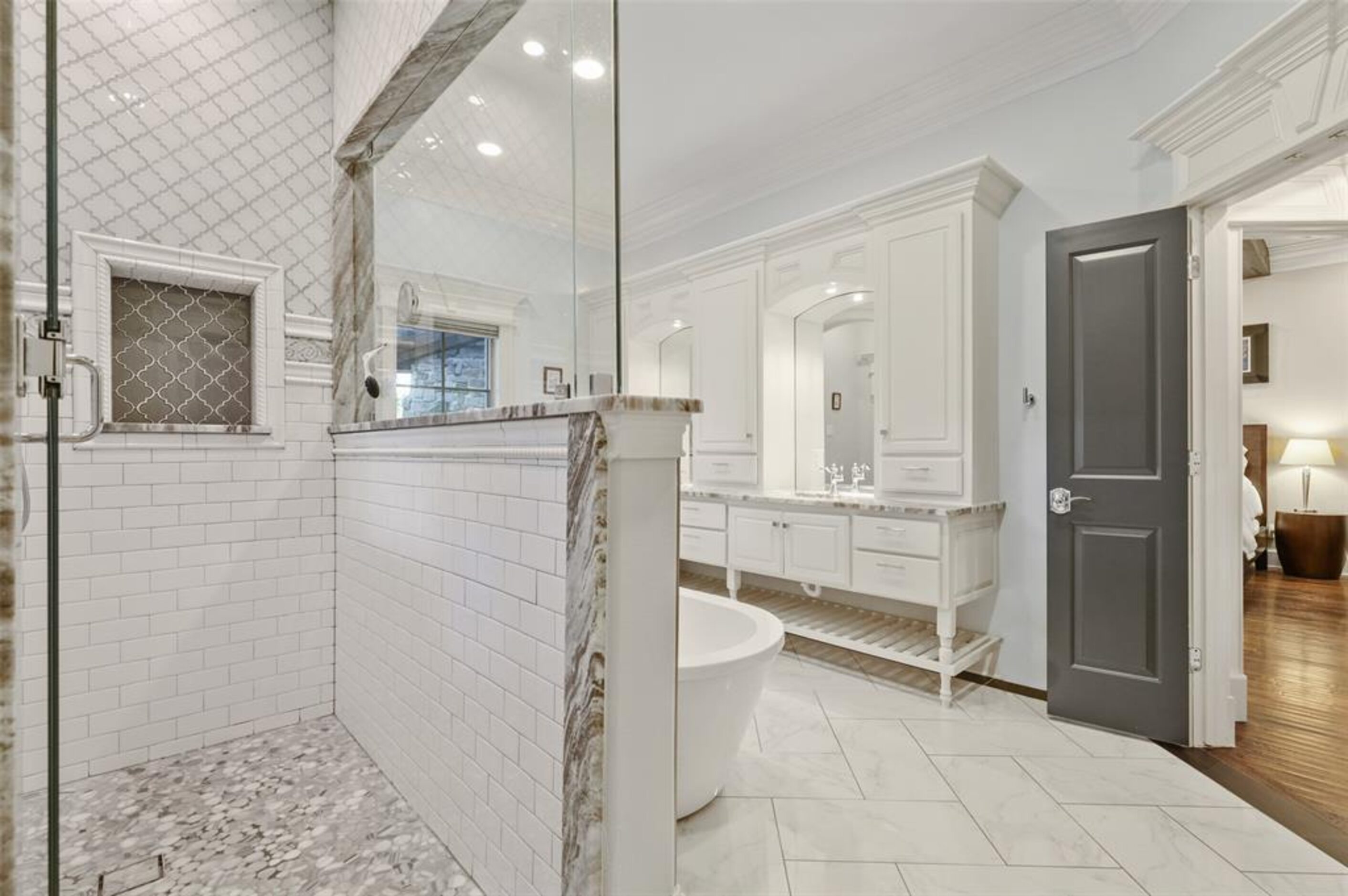 The primary bedroom includes an en-suite marble-accented bathroom with a large soaking tub...