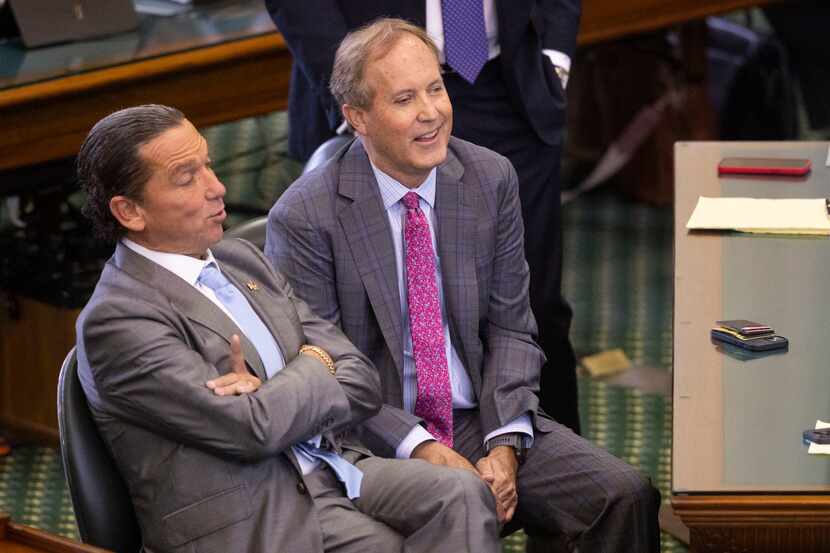 Texas Attorney General Ken Paxton (right) sits with defense attorney Tony Buzbee during his...