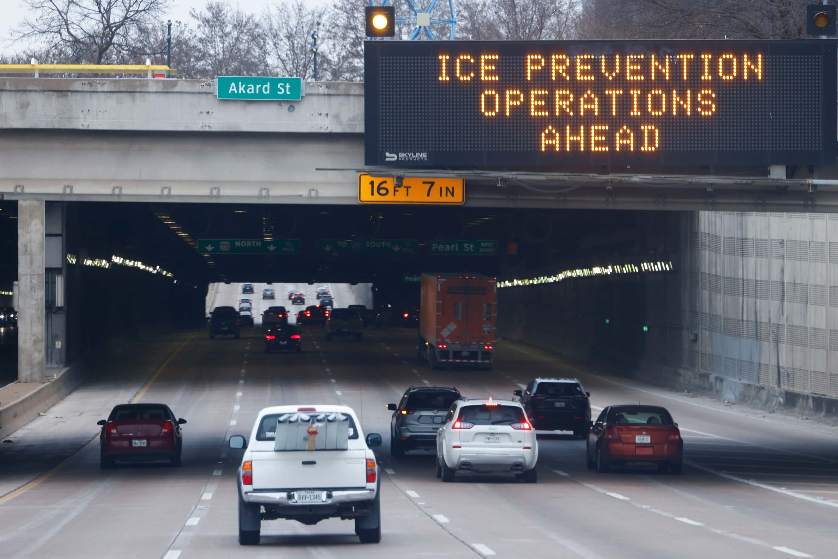 Winter weather warnings flash above traffic on Woodall Rodgers Freeway in downtown Dallas,...