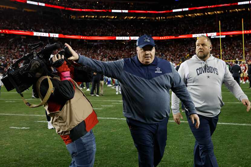 El entrenador en jefe de los Cowboys de Dallas, Mike McCarthy, empuja a un camarógrafo...