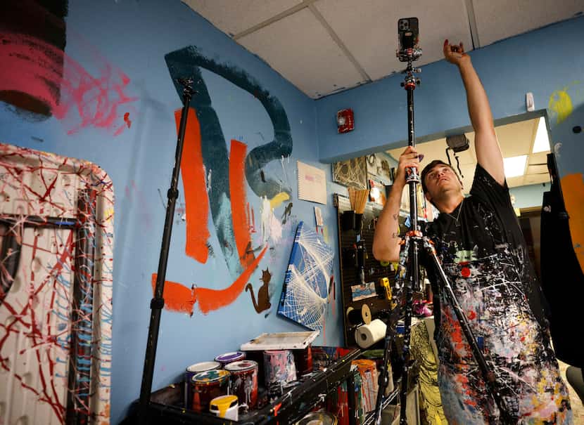 Newman sets his cellphone on a tripod before filming a pendulum painting video he'll post on...